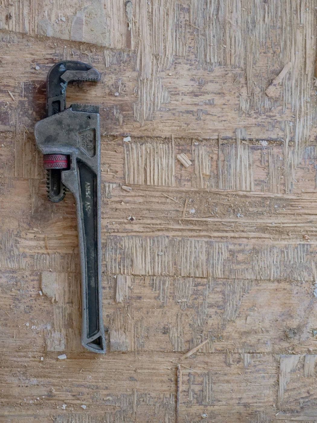 Clé à molette de plombier posée sur un établi en bois