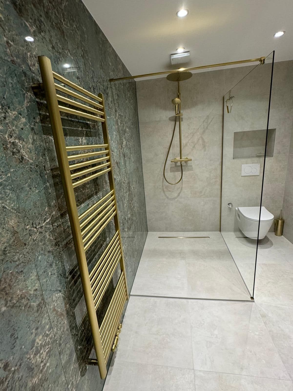 Douche en pierre verte avec sèche-serviettes doré, même rénovation que la double vasque